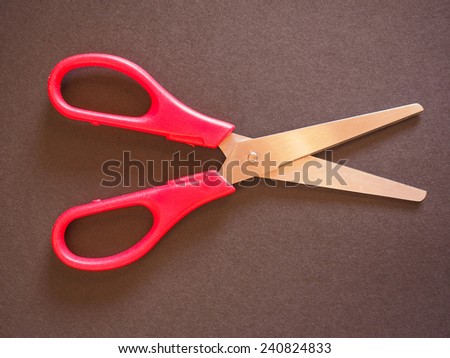Red scissors with cutting lame open over black background