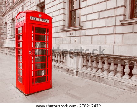 Vintage looking Red telephone box in London over desaturated black and white background