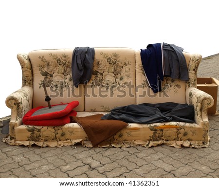 Old sofa with clothes used by poor homeless hobo