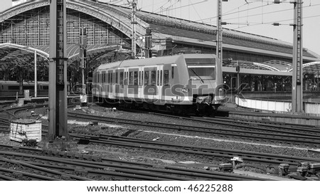 Trains in a large urban central station - (16:9 black and white)