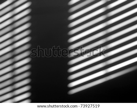 Sun lights and shadow on a room wall from a window roller shutter