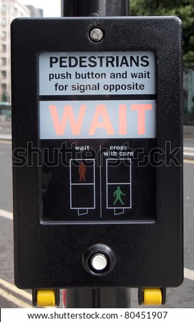 A pedestrian crossing sign - press button and wait for signal opposite London UK England United Kingdom English traffic warning signal