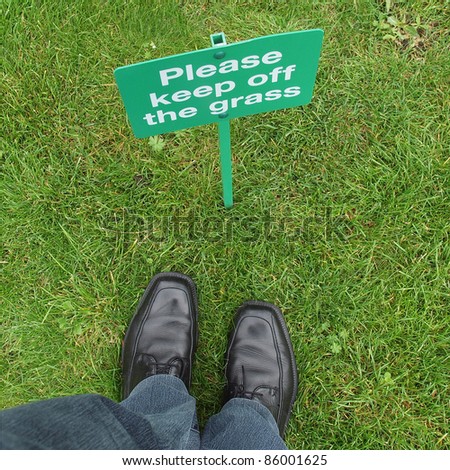 Keep off the grass sign in a meadow, with feet breaking the law
