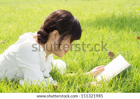 Beautiful young woman reading a book on nature