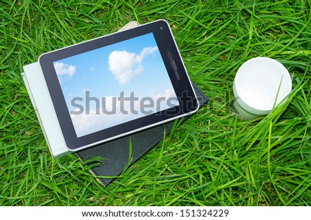 Tablet PC and books on the grass.