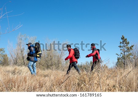 Three persons in the autumn sport hiking, walking and backpacking