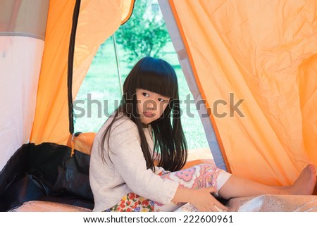 The little girl lying indoor of camping tent smiling