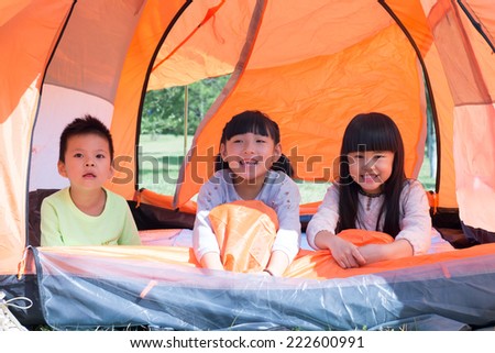 Children lying indoor of camping tent smiling