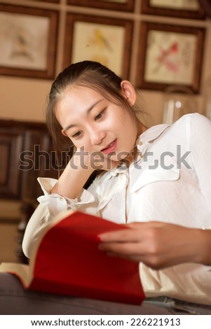 Reading her favorite book in cafe. Beautiful young woman reading book.