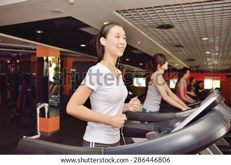 Woman training in a fitness club. While running while using headphones to listen to music