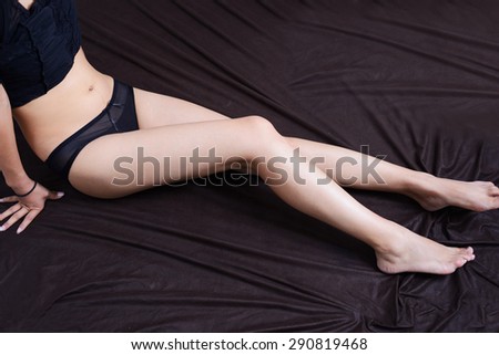 Sexy woman  smooth long legs posing  lying isolated on a black background