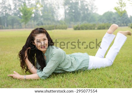 Happy old age woman bend over on the lawn.The park in the summer.