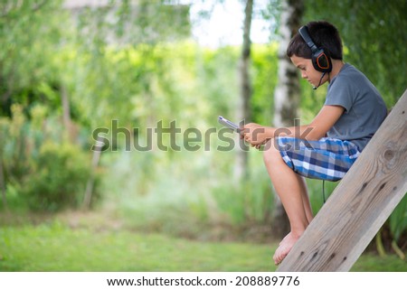 Child playing on the computer with headphones outdoor