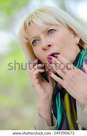 Senior woman frightened phoning outdoor