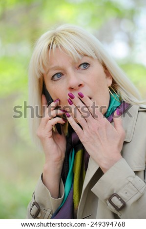 Senior woman frightened phoning outdoor