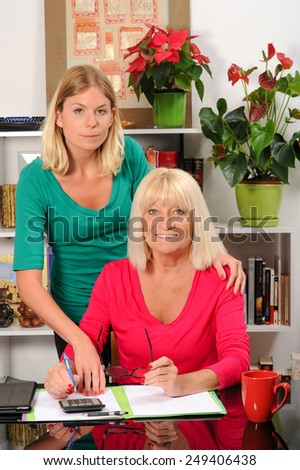 Mature woman helping elderly mother pay bills.