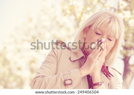 Senior woman blowing her nose outdoor