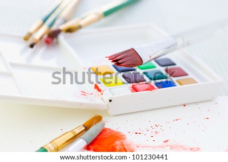 Image of paint brush over color paints on place for painting