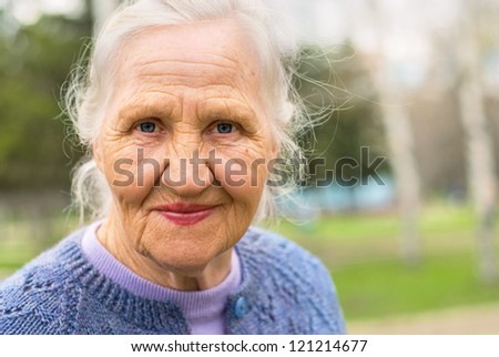 Portrait Of A Smiling Elderly Woman. A Photo On The Nature Background