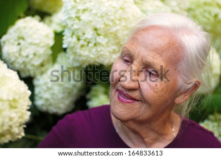 Portrait of the smiling elderly woman, in a garden