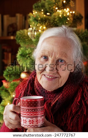 Elderly woman with cup of tea  near christmas tree
