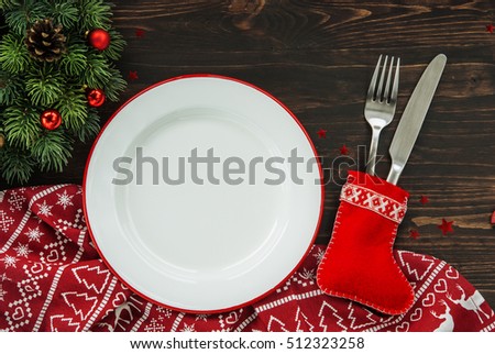 Christmas dinner background, plate, fork, knife and festive decoration on dark rustic wooden table, top view