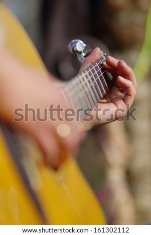 playing guitar, vertical, blurry foreground