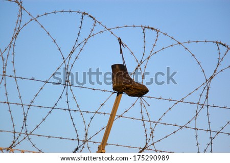 A lost boot hanging on a barbed wire