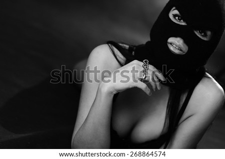 close up portrait of beautiful young woman in black sexy underwear, balaclava, lying on bed xxx