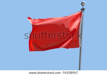 Red flag flying in a stiff breeze against a clear blue sky.