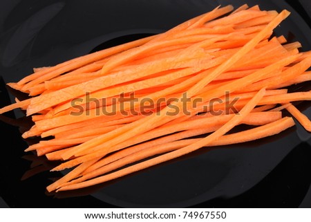 Pile of shredded carrots isolated on a black plate