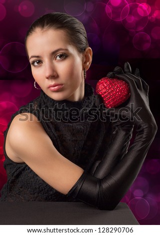 The woman in black gloves holding a red, shiny heart