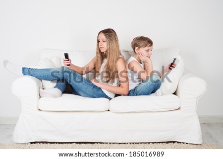 Children sit on the couch with a mobile phone
