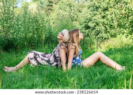Two women of different generations sitting on the grass. Mother and daughter