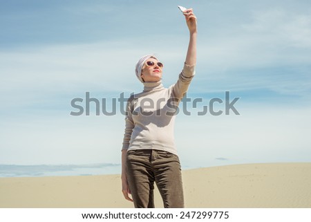 Woman holds a smartphone and makes selfie