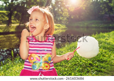 Joyful girl eating cotton candy in nature
