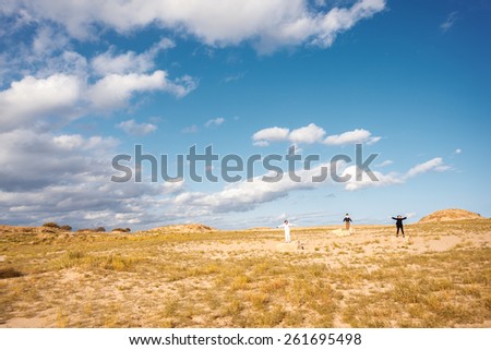 Landscape with people. Three people standing in a field on the rocks with arms raised