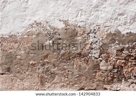 Grungy repaired damaged wall of house with white stucco and mortar
