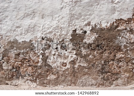 Grungy repaired damaged wall with white stucco and mortar