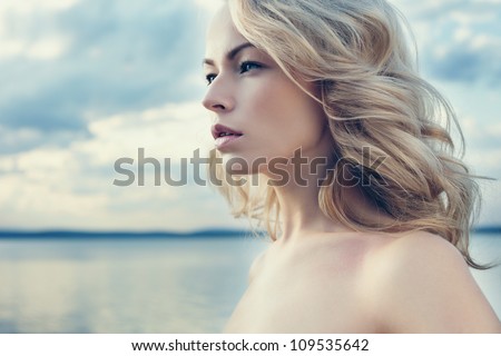 Beautiful young blond woman outdoors portrait near the lake