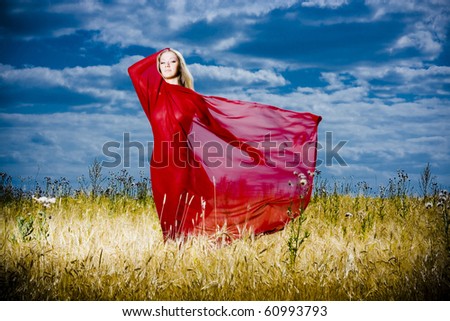 Portrait of romantic woman with a red tissue in a field