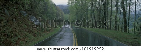 This is a rain soaked road showing bad weather. It is called the Foothill Parkway and is surrounded by green trees.