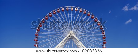 This is an aerial view of a giant Ferris wheel. It is a view of half the Ferris wheel against a blue sky.