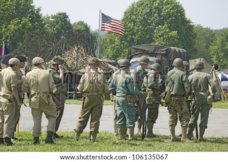 American soldiers with American flag flying in background at Mid-Atlantic Air Museum World War II Weekend and Reenactment in Reading, PA held June 18, 2008