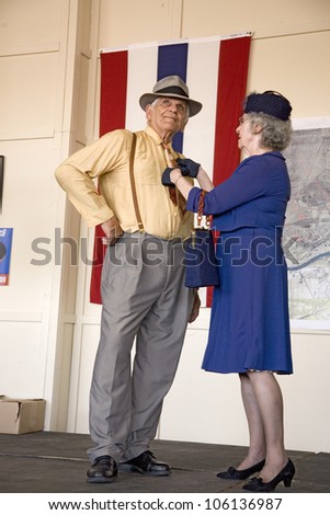 Older woman straightening the tie of her husband during a World War II reenactment of a fashion show at Mid-Atlantic Air Museum World War II Weekend and Reenactment in Reading, PA held June 18, 2008