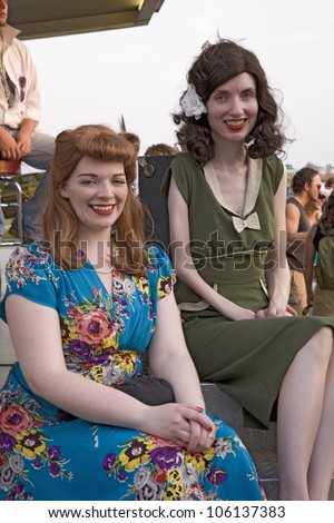 Two women smile as they are dressed in World War II 1940s vintage dresses at Mid-Atlantic Air Museum World War II Weekend and Reenactment in Reading, PA held June 18, 2008