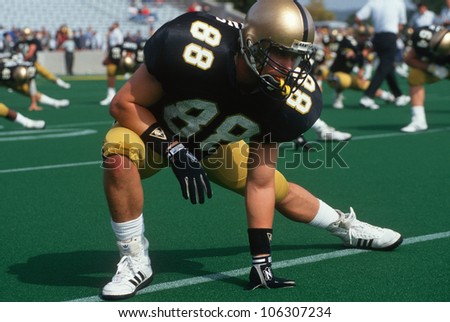 CIRCA 1992 - College football player doing warm-up stretches USA