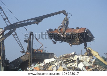 CIRCA 1993 - A wrecking crane lowering a demolished automobile onto a pile of junk, Atlanta, Georgia