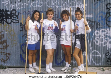 CIRCA 1990 - Four teenage girls participating in community cleanup on Clean and Green Day in East Los Angeles, California