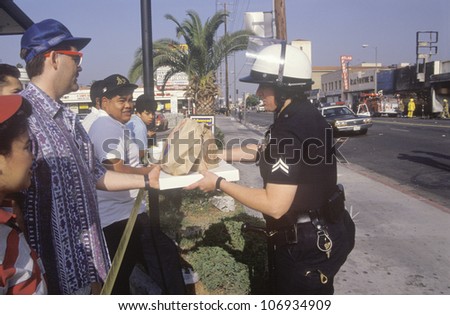 CIRCA 1992 - Community members giving lunch to policeman, South Central Los Angeles, California